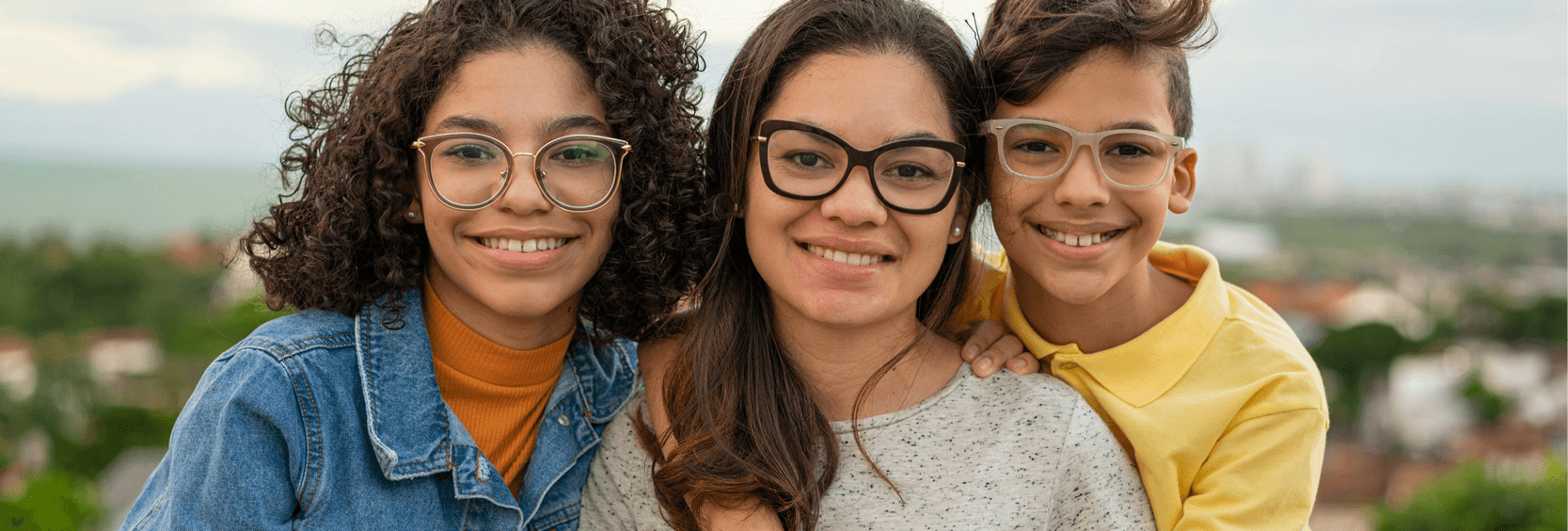 Closeup of sisters and brother wearing glasses and osing outside